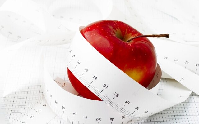 Measuring tape and red apple. Symbolic.